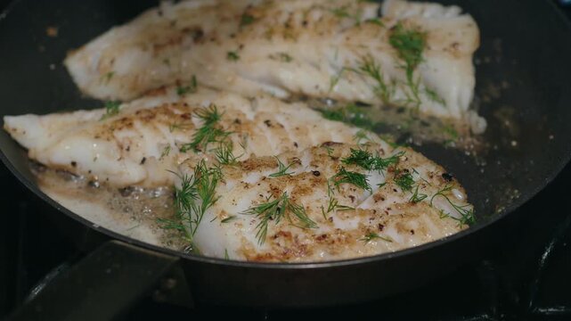 Fresh dill sprinkled over cod fillets as they sear in a skillet