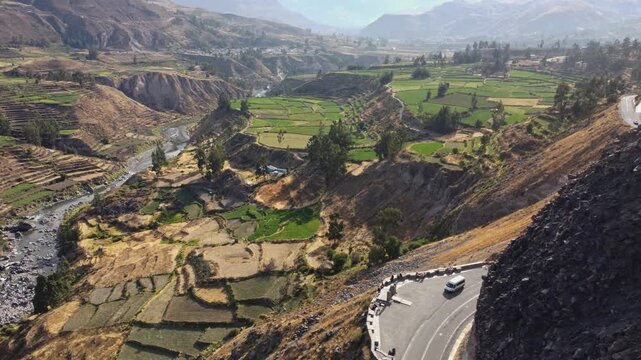 Aerial drone panning shot revealing Colca Valley from rocky mountain foreground, Peru