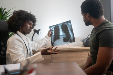 Black woman doctor explaining lung scan results to patient in medical office