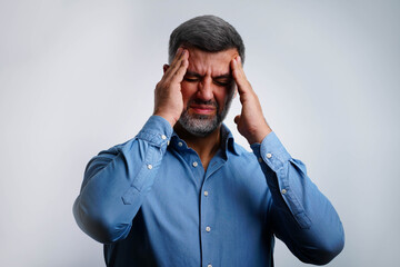 Portrait of man isolated on gray background, suffering from severe headache, pressing fingers to temples with closed eyes