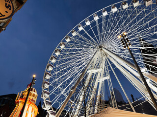 Ferris wheel at Manchester city night scene with illuminated rides and bright urban lights