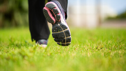 Athletic woman walking on grass in sports shoes
