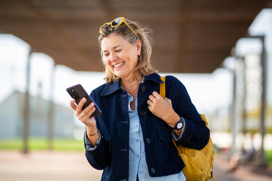 Mature woman smiling while checking smartphone outdoors