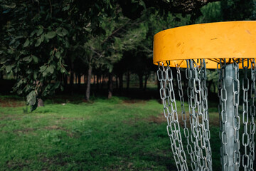 dark forest background and bright yellow discgolf basket