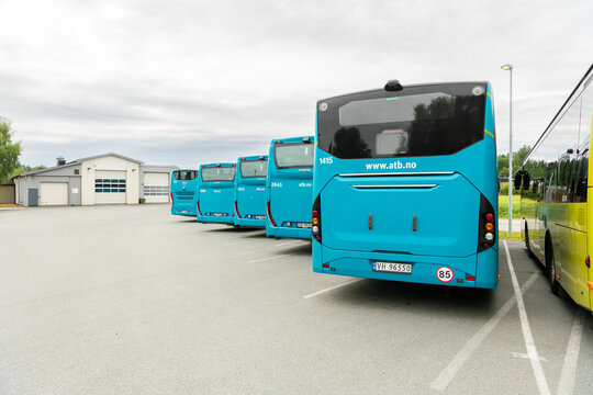 26 july 2025, Levanger, Norway. Row of electric public busses, atb, back view, charging at a charging station. Charging electicity cable is visible and connected, plugged into the socket of the bus.