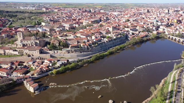 Scenic drone view of ancient walled Spanish city of Zamora on bank of Duero River overlooking Romanesque medieval cathedral on sunny spring day. High quality 4k footage