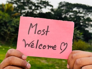 Welcome handwritten sign taken on hand, Most welcome sticky note sign with green background