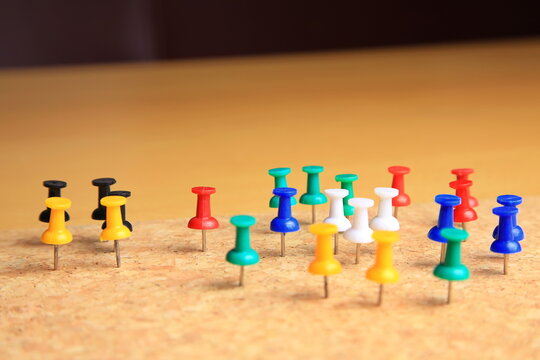 Bunte Stecknadeln stehen geordnet auf einer Korkplatte. Die kr&auml;ftigen Farben und klare Anordnung erzeugen ein lebendiges, strukturiertes Bild mit Fokus auf Organisation und Ordnung.