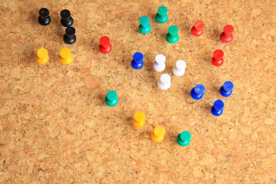 Bunte Stecknadeln stehen geordnet auf einer Korkplatte. Die kr&auml;ftigen Farben und klare Anordnung erzeugen ein lebendiges, strukturiertes Bild mit Fokus auf Organisation und Ordnung.