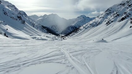 Majestic wide angle view captures the cold, snowy mountain valley marked by fresh winter sport tracks.