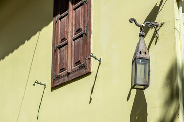 Authentic Ottoman-era vintage wall lantern with pyramidal metal hood and glass cube in historic Kaleici. Historic street lighting detail under sunny Mediterranean sky. Antalya, Turkey.

