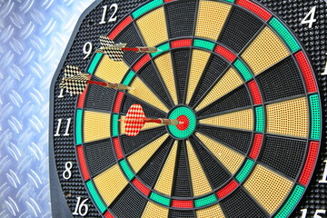 Drei Dartpfeile stecken pr&auml;zise in der Dartscheibe. Die kr&auml;ftigen Farben und der metallische Hintergrund betonen den Moment sportlicher Konzentration.