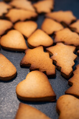 Freshly baked Christmas cookies laying spread on clean black kitchen table without glazing or decorations