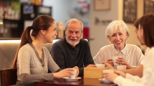 Meeting big family in cafe. Young and senior relatives chatting sweetly during tea party, discussing news, sharing their impressions. Shopping Mall food court - meeting place for friends