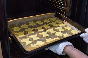 Pieczenie świątecznych ciasteczek w kształcie gwiazdek i aniołków, wkładanie ciasteczek do piekarnika – przygotowania do Bożego Narodzenia w domowej kuchni © Michał Kiełpiński