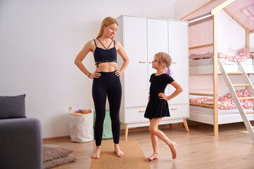 Obraz premium Young woman and girl practicing dance poses at home