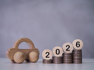 Wooden toy car and Wooden blocks with number 2026 on stack of coins. The concept of saving money to success transportation, Car loan in year 2026