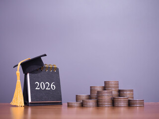 Study goals. 2026 desk calendar with graduation hat and stack of coins. The concept of saving money for education, student loan, scholarship, tuition fees in year 2026
