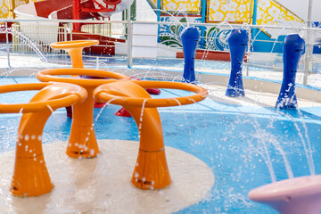 Children enjoy water play at a colorful splash pad featuring bright structures and fountains, providing a fun atmosphere for outdoor activity © Creative_Bird