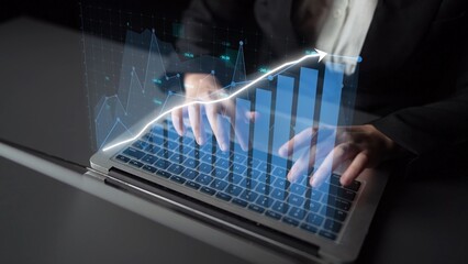 A business professional types on a laptop with digital graphs and data overlays illustrating financial growth and analysis, representing modern technology in the workplace. Copula