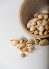Pistachios spilled out of a clay bowl, selective focus