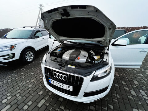 Audi Q7 with open hood showing engine bay in a parking lot