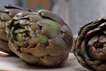 Fresh Purple Artichokes on Cutting Board with Mediterranean Ingredients: Olive Oil, Lemon, and Garlic
