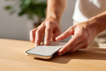 Fototapeta premium Person using smartphone on wooden table