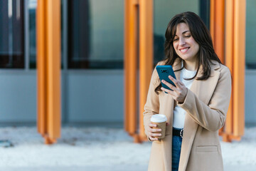 Woman businesswoman communicating with smartphone holding coffee