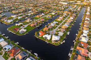 Sunset aerial view of Punta Gorda wealthy neighborhood. Expensive residential homes along canals reflect warm evening sky.