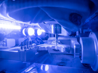 Automated dental milling unit crafting custom prosthetic model from zirconia block in high-tech lab under blue lighting.