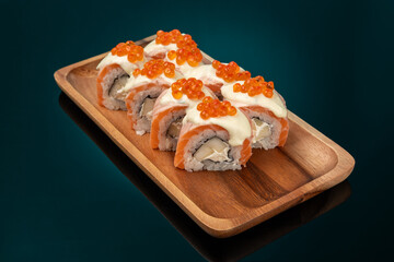 Sushi roll with salmon and red caviar, dark background with azure backlight