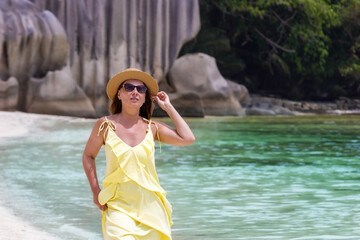 Woman in yellow dress enjoying a tropical beach vacation with unique rock formations