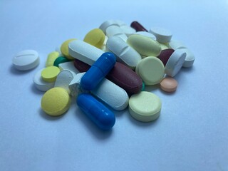 Pills and capsules of various colors and shapes arranged in a photorealistic display, representing medicine and treatment.