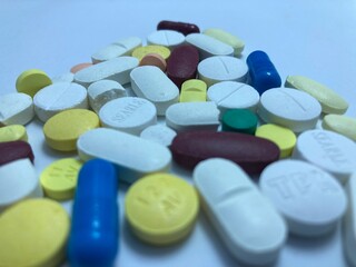 Pills and capsules of various colors and shapes arranged in a photorealistic display, representing medicine and treatment.