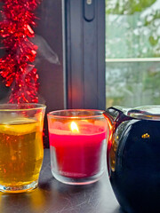Christmas still life with burning candles on the windowsill and Christmas decorations. Tea