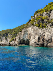 Vertical Greek Scenery of Turquoise Ionian Sea and Green Trees and Rocky Cliff in Zakynthos. Summer Sunny Day of Rock Formation with Water in Greece.