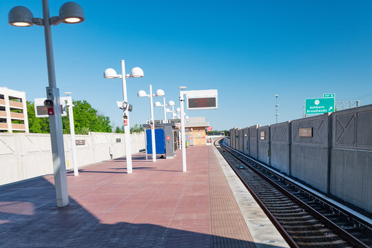 New Empty Ashburn Metro station platform with train track and bright blue sky in Virginia
