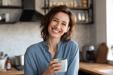Beautiful woman smiling with a cup of coffee in the kitchen of her home