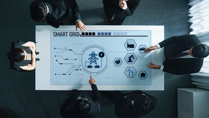 Business professionals collaborate around a digital table, examining smart grid technology and visual data. The scene showcases teamwork and the future of energy management. Trope