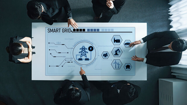 Business professionals collaborate around a digital table, examining smart grid technology and visual data. The scene showcases teamwork and the future of energy management. Trope - Powered by Adobe