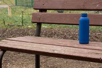Reusable water bottle standing alone on wooden park bench