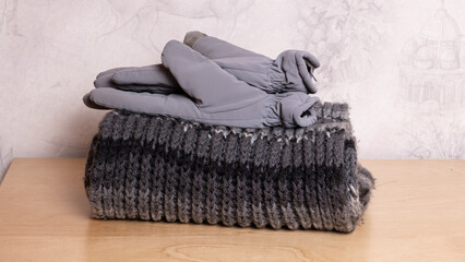Stack of winter scarf and gloves placed on wooden furniture