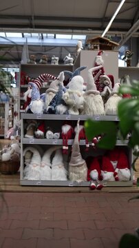 Vertical screen rows of soft christmas gnome figures fill store shelves with red and white winter dolls creating cozy festive shopping scene