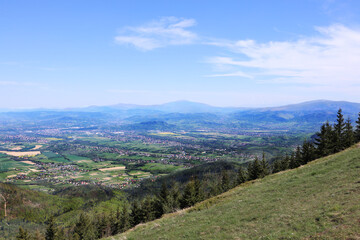 Panoramic view of Beskid Slaski mountains and valley from grassy slope on Skrzyczne summit
