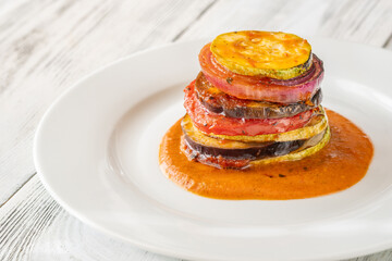 Elegant vertical ratatouille tower layered with colorful vegetables on white plate