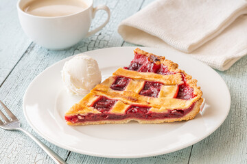 Cherry pie slice with melting ice cream and coffee on white plate