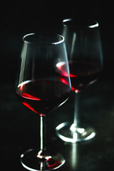 Two red wine glasses with dark background creating an elegant atmosphere for celebrations and...