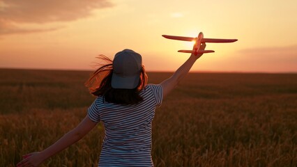 Cheerful girl plays with toy airplane in plowed field. Happy child runs with toy airplane across field. Child dreams flying, childhood fantasies. Little girl wants to become pilot travel. Slow motion. © Victoriia