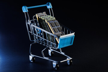 Ram ddr memory modules for laptop in toy shopping cart on black background © Dmytro Hai
